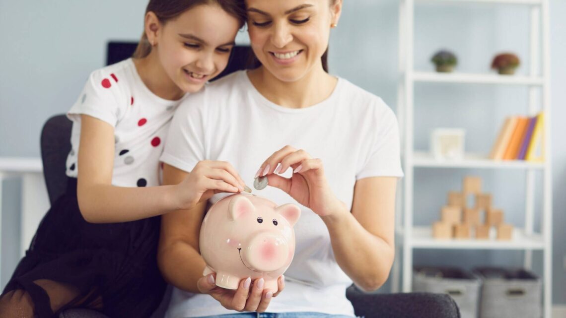 mother and daughter saving money into piggy bank